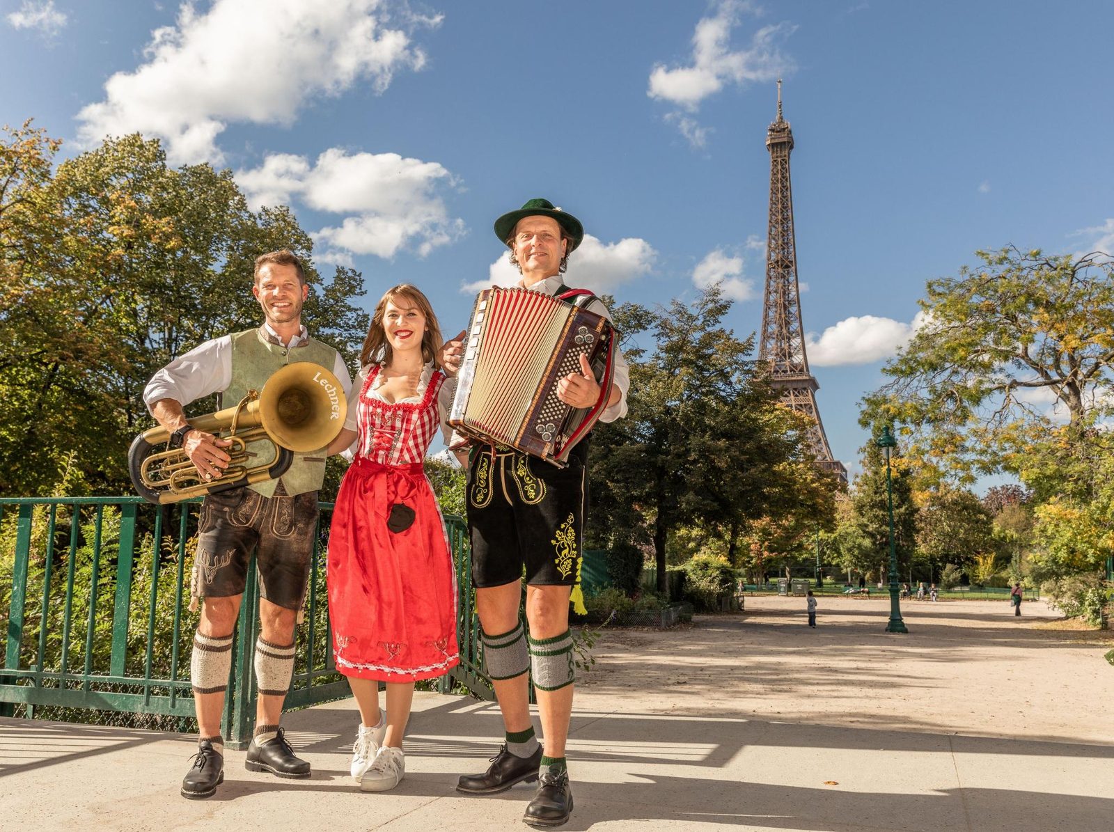 Orchestre bavarois en tenue traditionnelle (accordéon, tuba, dirndl) devant la Tour Eiffel à Paris